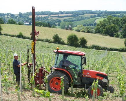 Tractor in vineyard fitting metal posts into the ground
